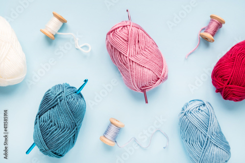 Multicolored crochet hooks with balls of yarn on a blue background.