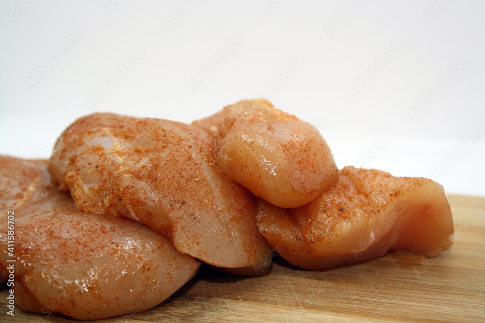 Chicken fillet pieces on a wooden board.