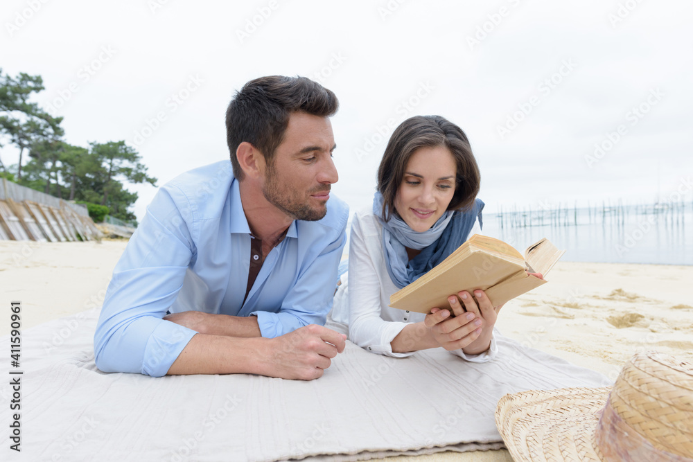 portrait of happy couple reading book on summer beach portrait of happy couple reading book on summer beach