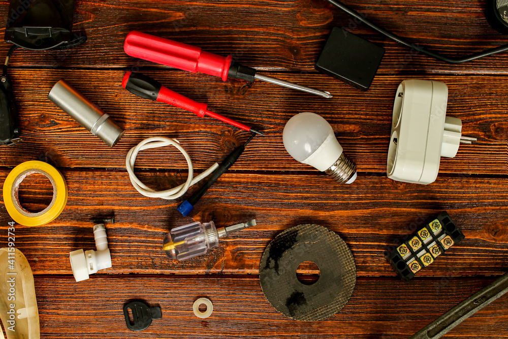 Various electrical supplies on a wooden table. Repair of electrical equipment at home with your own hands. Getting ready to repair the wires. Various electrical supplies on a wooden table. Repair of electrical equipment at home with your own hands. Getting ready to repair the wires.