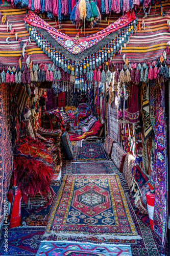 Turkish bazaar carpet shop entrance decorated with various handmade rugs with colorful tassels. Ornate weaved carpets. Ethnic pattern rugs. Traditional Asian textures