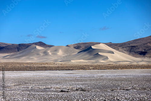 Landscape of Sand Mountain OHV park dune from far away lit by morning light with salt flats in the foreground