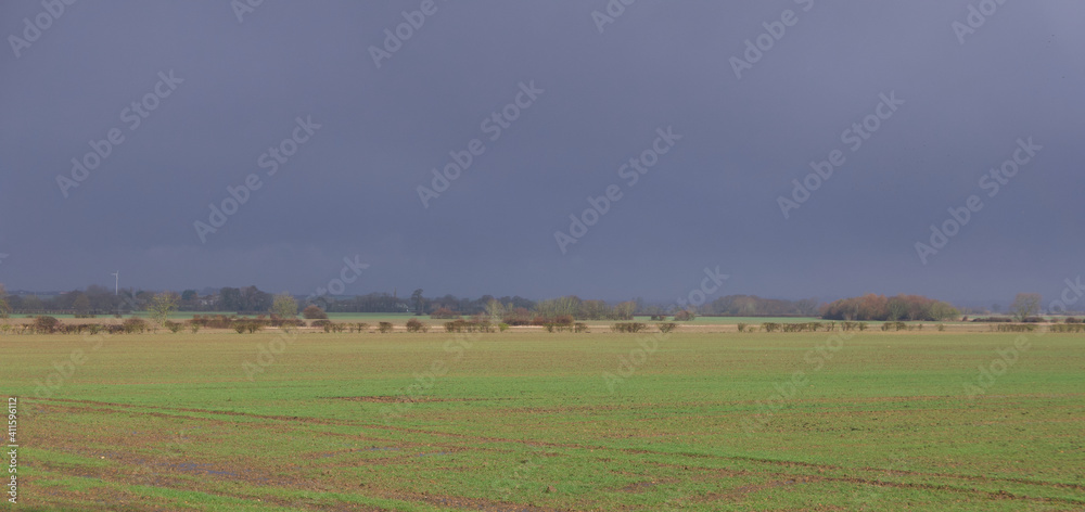 English countryside with deep grey blue sky and green field with copy space