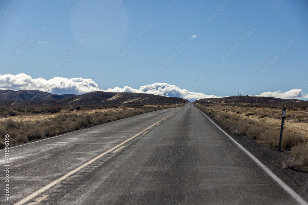 Road runs through empty desert and sagebrush heading toward the mountains Road runs through empty desert and sagebrush heading toward the mountains