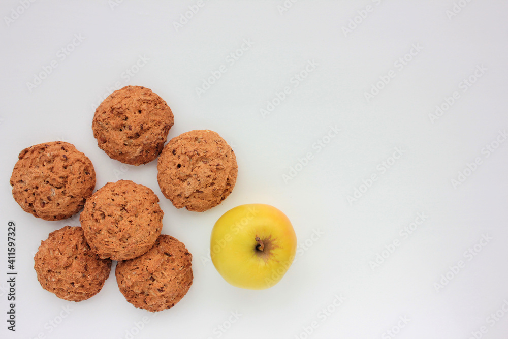 Homemade oatmeal cookies and golden apple on white table. Overhead view of oat biscuits and fresh fruits on white background with copy space Homemade oatmeal cookies and golden apple on white table. Overhead view of oat biscuits and fresh fruits on white background with copy space