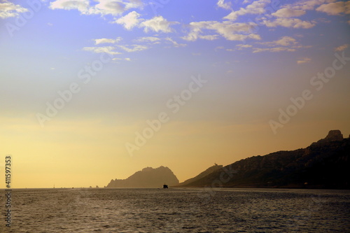 Sunset on the sea with the coast and a ship in backlight