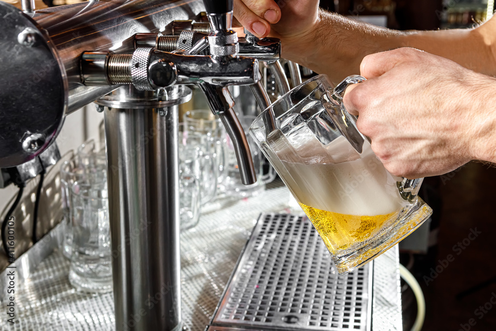 Pouring beer into a mug in a beer bar close-up. Beer bottling in the restaurant. The bar counter.