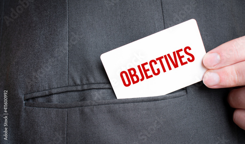 Card with Objectives text in pocket of businessman suit. Investment and decisions business concept.