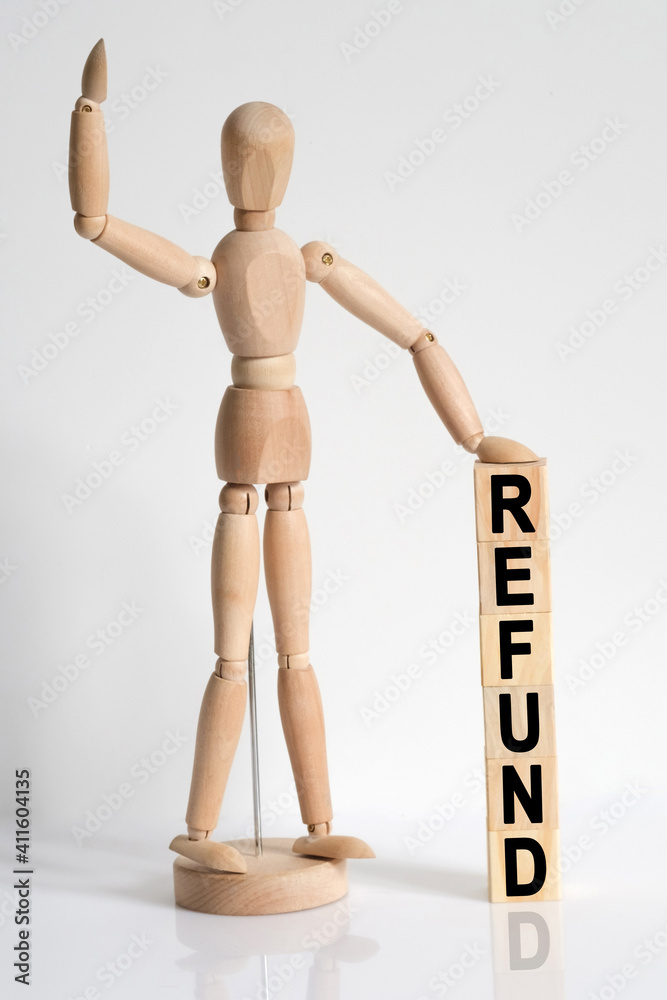 The wooden man raised his hand, and under his left hand he has cubes with the inscription - REFUND The wooden man raised his hand, and under his left hand he has cubes with the inscription - REFUND