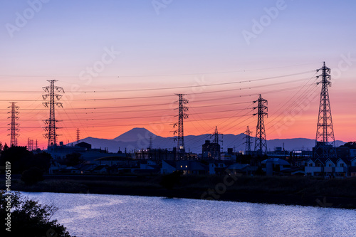 夕焼けの中、富士山と送電塔のシルエット、青い空を映す水面
