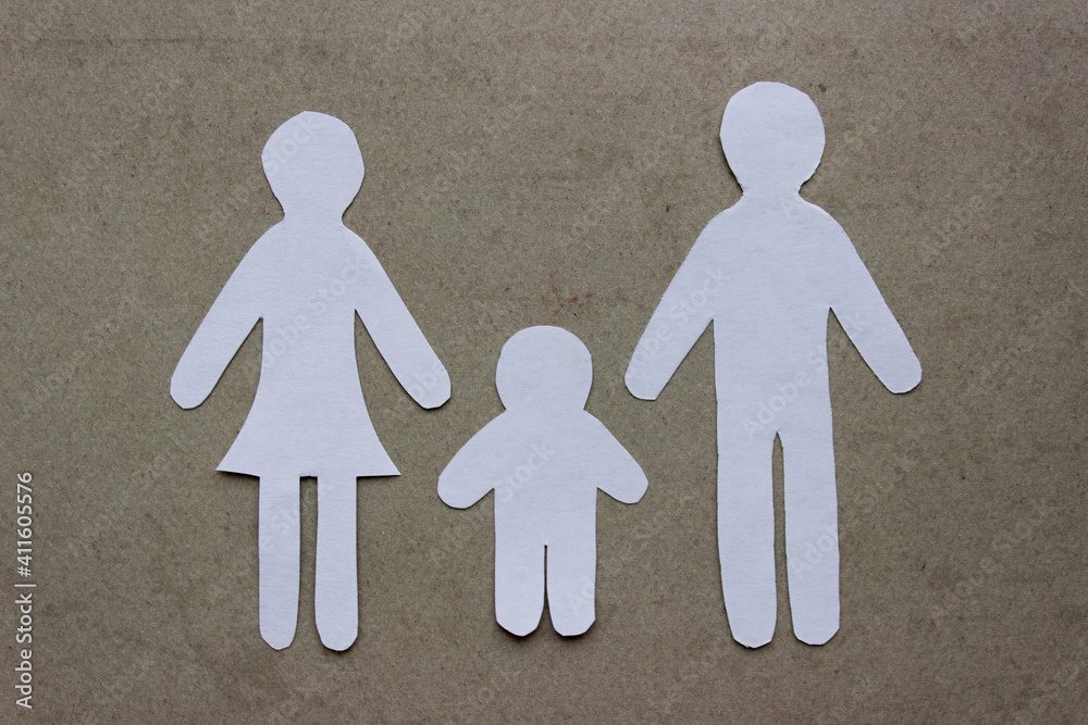 Silhouettes of family cutting from white paper on beige background. Mom, dad and son. Family with a child Silhouettes of family cutting from white paper on beige background. Mom, dad and son. Family with a child