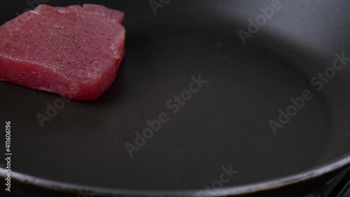 Mens hand puts raw tuna steaks in a frying pan. Cooking fish. 4k video. Healthy diet food
