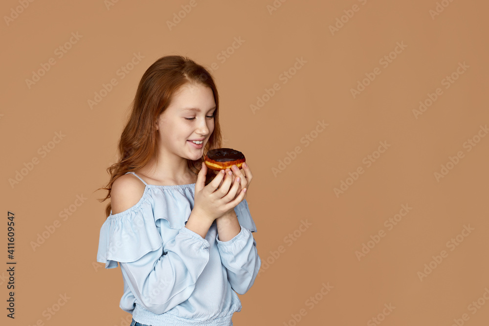 attractive child girl tastes yummy chocolate donut isolated on studio background. copy space attractive child girl tastes yummy chocolate donut isolated on studio background. copy space