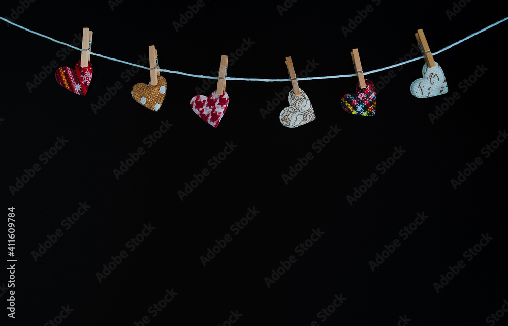 a group of fabric hearts fastened with clips on a white rope, on a black background. Valentine concept. Romantic and love. a group of fabric hearts fastened with clips on a white rope, on a black background. Valentine concept. Romantic and love.