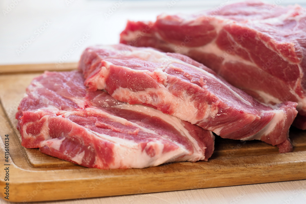 Raw piece of beef and slices on wooden cutting board