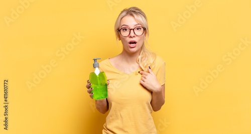Foto blonde woman looking shocked and surprised with mouth wide open, pointing to sel