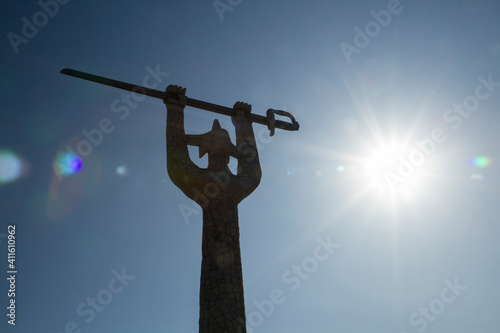 Art and history. Giant monument in honor to the victory at Chacabuco battle in 1817, that lead to Chile's independence. Huge stone statue of a man holding a sword at sunset with a lens flare.   photo