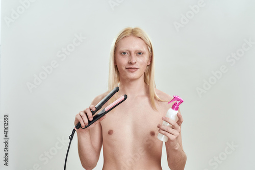 Young caucasian man holding hair straightener and fixation foam