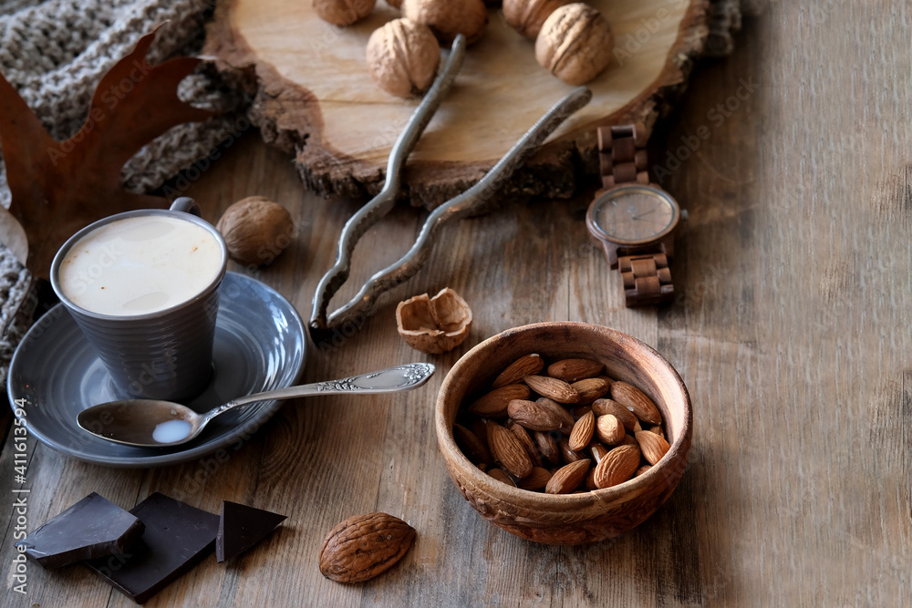 cup of coffee, different kinds of nuts, walnut, hazelnuts, almonds on old wooden table boards, edible seed kernels, food concept, confectionery ingredient