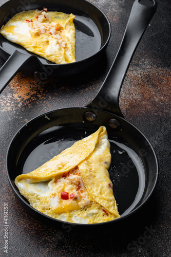 Thai  Asian omelette, fresh red chilli, brown and white crabmeat, lemon, Cheddar cheese, eggs, on frying iron pan, on old dark rustic background