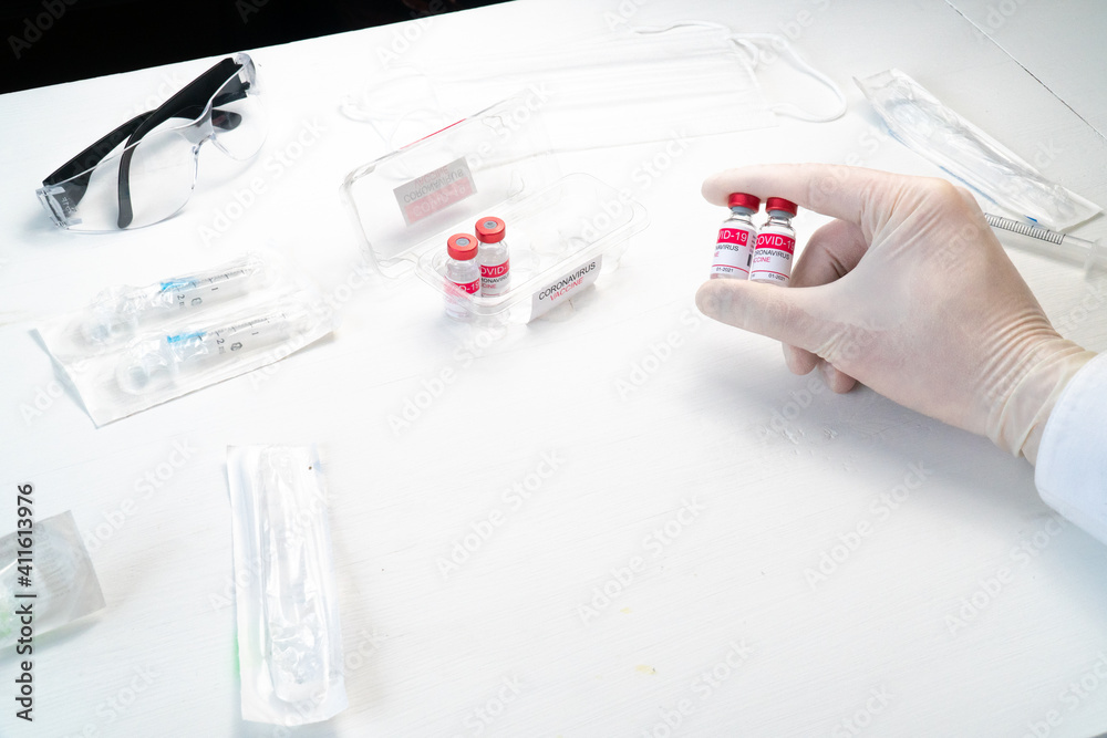 Fototapeta premium doctor hand in white glove holding glass bottle with coronavirus vaccine. Concept of treatment of coronavirus infection, COVID-19 vaccination