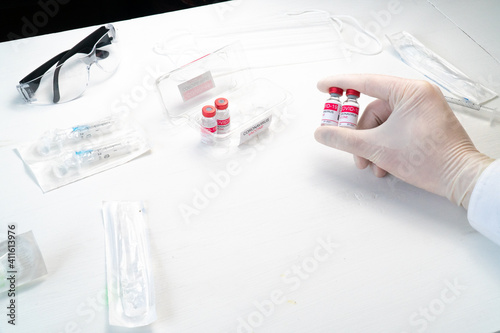 doctor hand in white glove holding glass bottle with coronavirus vaccine. Concept of treatment of coronavirus infection, COVID-19 vaccination