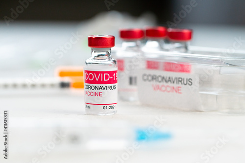 glass bottle with coronavirus vaccine on white table in clinic. Concept of treatment of coronavirus infection, COVID-19 vaccination