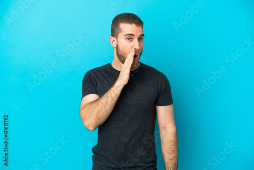 Photos Young handsome caucasian man isolated on blue background whispering something wi