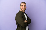 Young handsome caucasian man isolated on purple background with arms crossed and happy