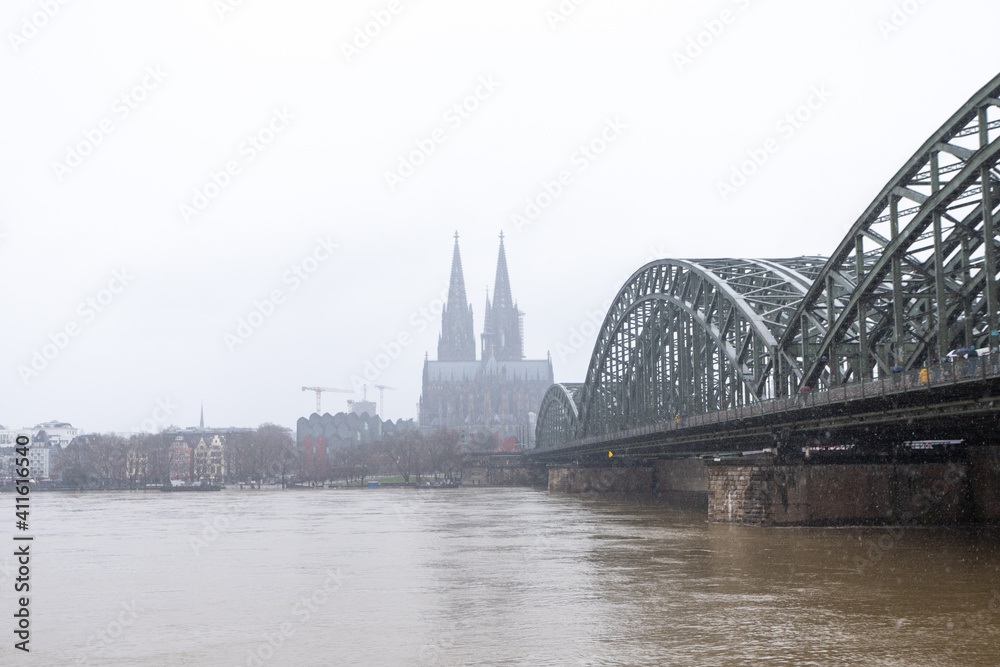 panorama of Cologne with cathedral and hohenzollern bridge at snowy weather. rhine river with high water