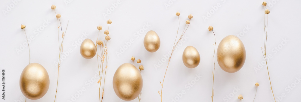 Obraz premium Stylish golden eggs easter concept. Easter gold eggs with golden dried flax linum bunch white background. Flat lay trendy easter. Happy easter card. Copy space for text