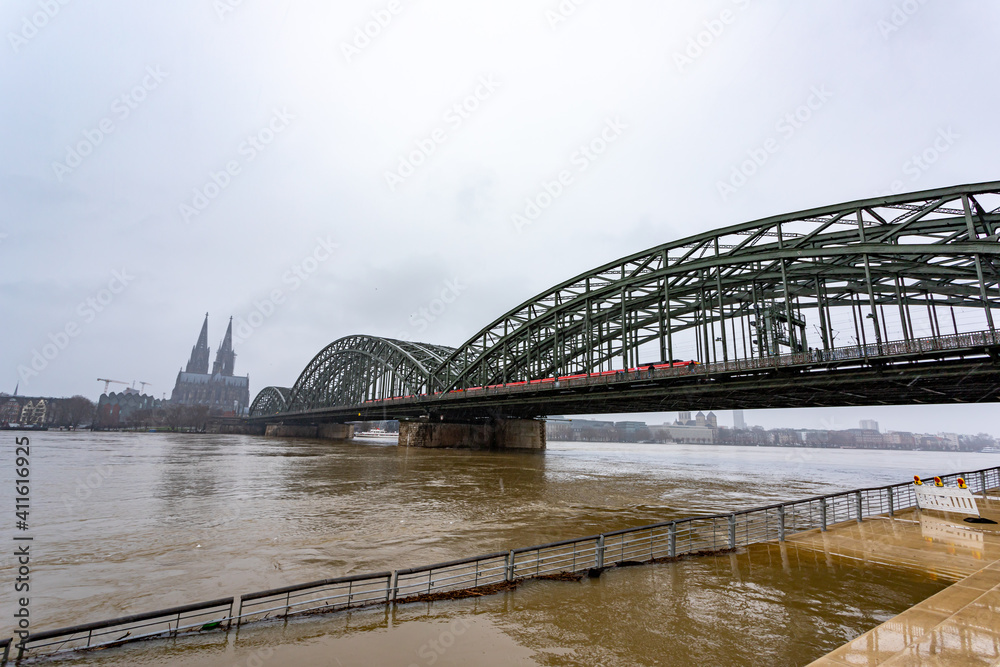 panorama of Cologne with cathedral and hohenzollern bridge at snowy weather. rhine river with high water