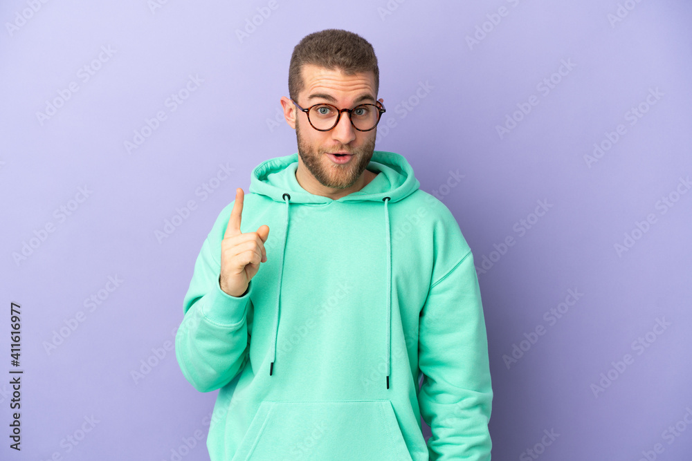 Young handsome caucasian man isolated on purple background intending to realizes the solution while lifting a finger up Young handsome caucasian man isolated on purple background intending to realizes the solution while lifting a finger up