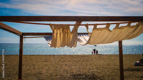 Cama de playa de madera con cortinas en una playa de Marbella