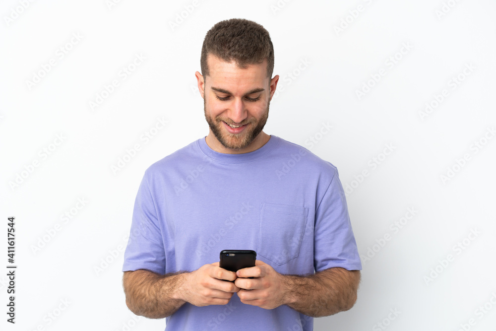 Young handsome caucasian man isolated on white background sending a message or email with the mobile Young handsome caucasian man isolated on white background sending a message or email with the mobile