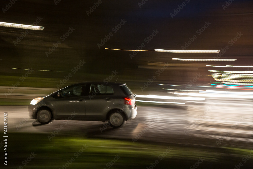 Car traveling at night in urban traffic, blur effect to simulate motion at high speed, concept of danger and drunk driving