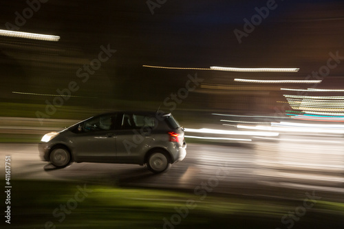 Car traveling at night in urban traffic, blur effect to simulate motion at high speed, concept of danger and drunk driving