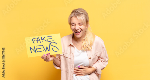 blonde woman laughing out loud at some hilarious joke, feeling happy and cheerful, having fun photo