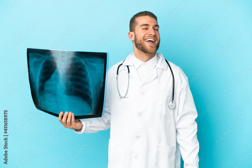 Professional traumatologist isolated on blue background laughing Professional traumatologist isolated on blue background laughing