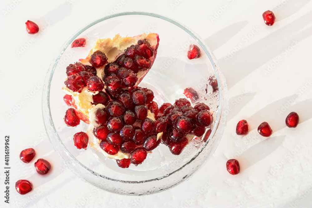 Pomegranate seeds close-up in a glass vase on a white background. Top view of the composition of pomegranate seeds. Bright sunlight, creative layout. The concept of freshness, summer, healthy food. Pomegranate seeds close-up in a glass vase on a white background. Top view of the composition of pomegranate seeds. Bright sunlight, creative layout. The concept of freshness, summer, healthy food.