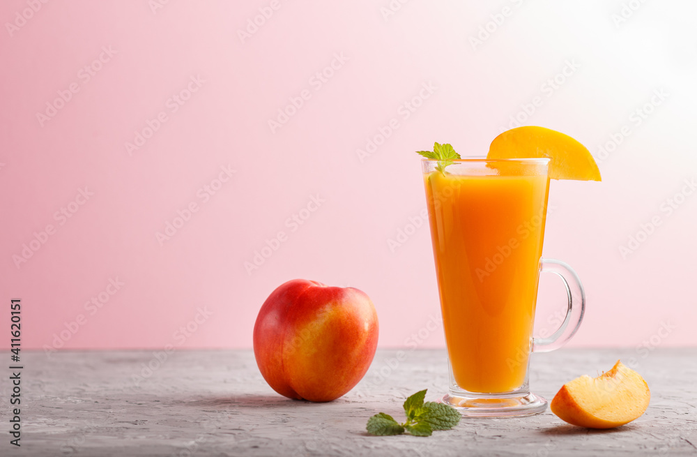 Glass of peach juice on a gray and pink background. Side view Glass of peach juice on a gray and pink background. Side view
