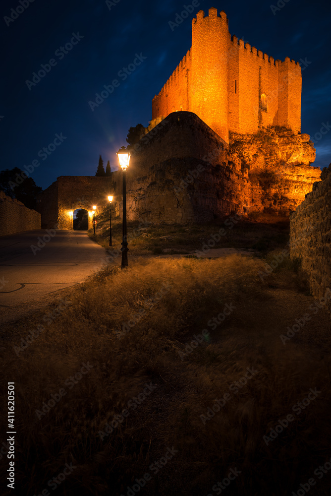 Illuminated street of the fortified city of Alarcon with the illuminated castle on top of the hill at night, Cuenca, Spain