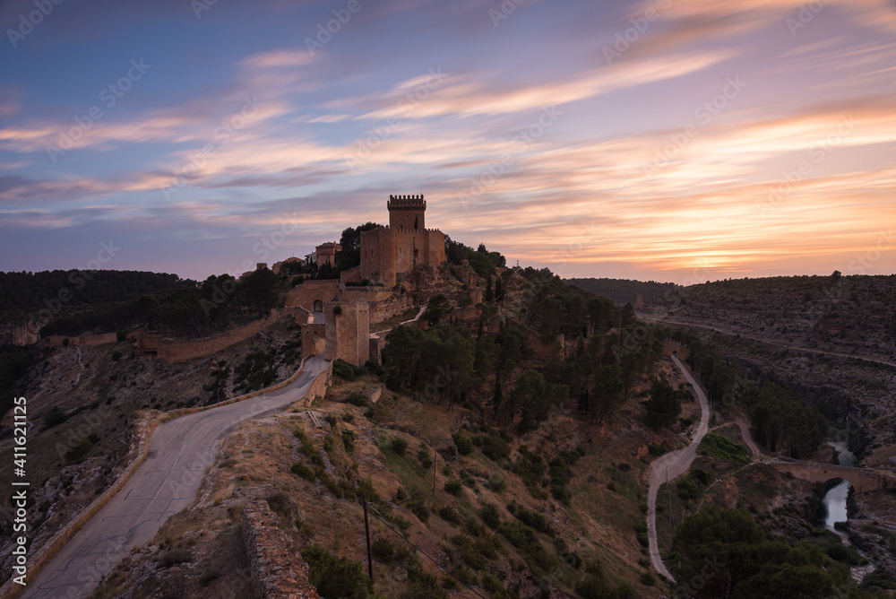 Landscape with the fortified city of Alarcon with its watchtowers and the castle on top of the hill in a colorful sunset, Cuenca, Spain