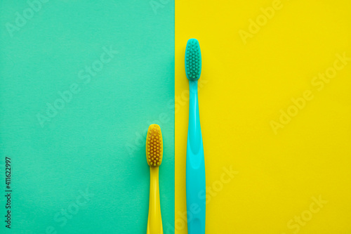 Two toothbrushes  yellow and green on a yellow and green background.