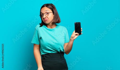 Bild auf Leinwand young hispanic woman shrugging, feeling confused and uncertain, doubting with ar