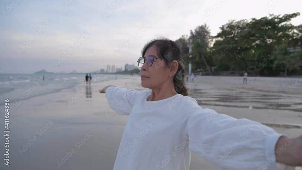 Travel concept of 4k Resolution. An asian old woman is breathing happily on the beach. Travel concept of 4k Resolution. An asian old woman is breathing happily on the beach.