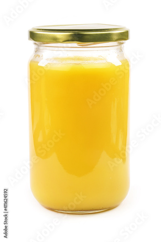Homemade ghee in jar and wooden spoon .   Ghee is purified butter.    isolated on white background.  photo