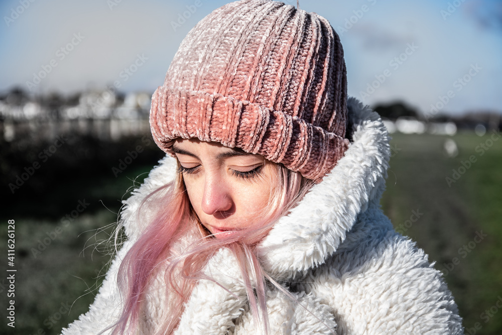 Young girl or woman with a pink hat and a white coat in winter. 