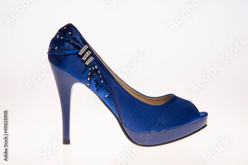 Elegant blue high-heeled shoe adorned with sequins and diamonds. Shoe placed in front of white background.