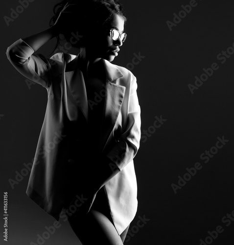 Stylish sexy brunette in white jacket on a dark background
